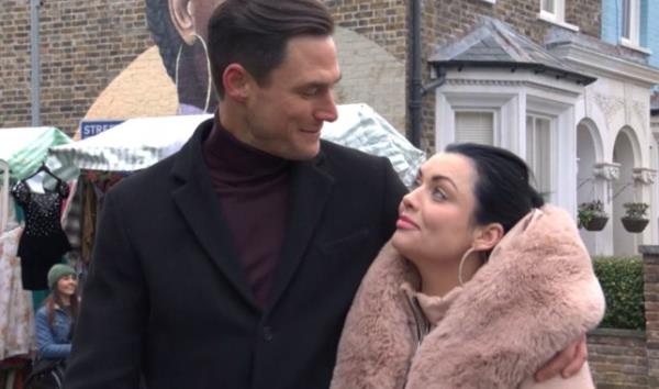 Zack and Whitney looking at each other as they walk through Albert Square in EastEnders